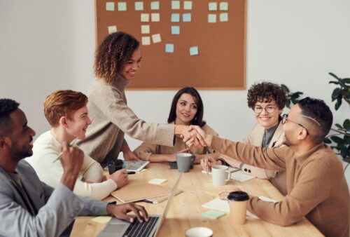 Équipe souriante qui accueille une nouvelle collègue autour d'une table de travail