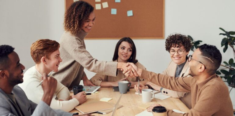Équipe souriante qui accueille une nouvelle collègue autour d'une table de travail