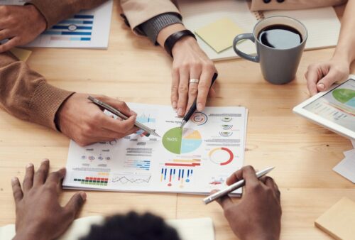 Collègues autour d'une table analysant des graphiques, illustrant un agent IA pour le briefing client avant une rencontre
