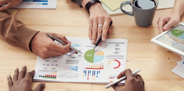 Collègues autour d'une table analysant des graphiques, illustrant un agent IA pour le briefing client avant une rencontre