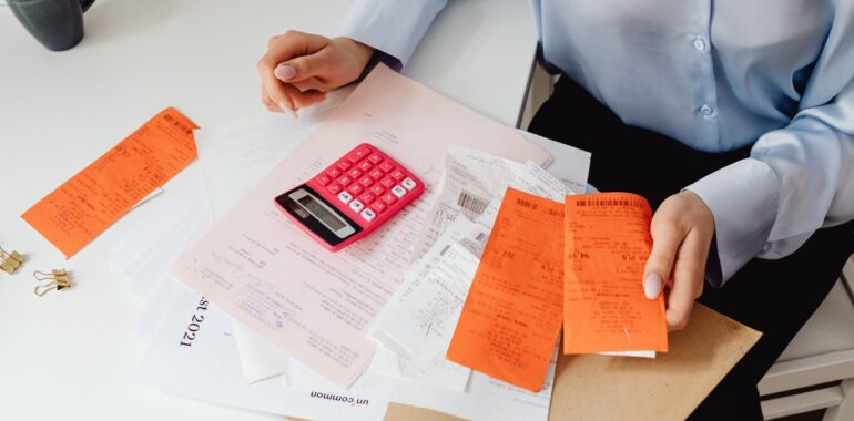 Personne triant des reçus avec une calculatrice rose, illustrant un agent IA pour les notes de frais