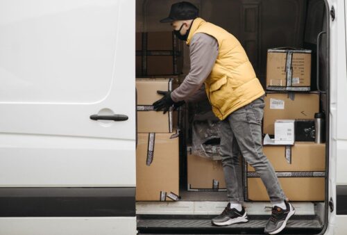Livreur organisant des colis dans une camionnette, illustrant la planification des techniciens sur le terrain
