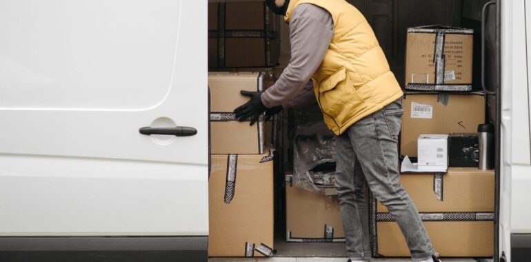 Livreur organisant des colis dans une camionnette, illustrant la planification des techniciens sur le terrain