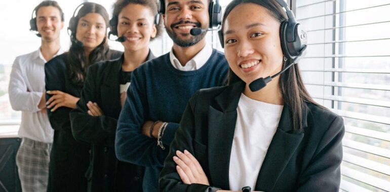 Équipe de service à la clientèle souriante portant des casques-microphones dans un bureau