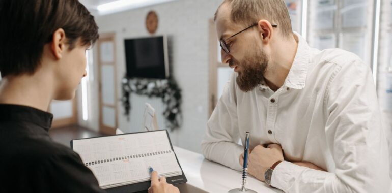 Réceptionniste montrant un carnet de rendez-vous à un client, illustrant un agent IA pour les rendez-vous