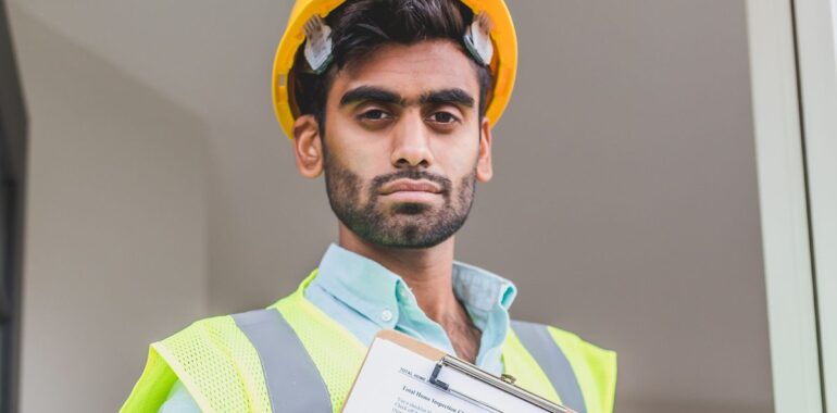 Entrepreneur en casque de chantier et dossard de sécurité tenant une planchette avec des documents
