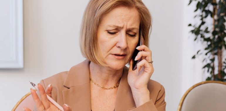 Femme d'affaires au téléphone devant son ordinateur portable, illustrant un agent IA pour le suivi des prospects