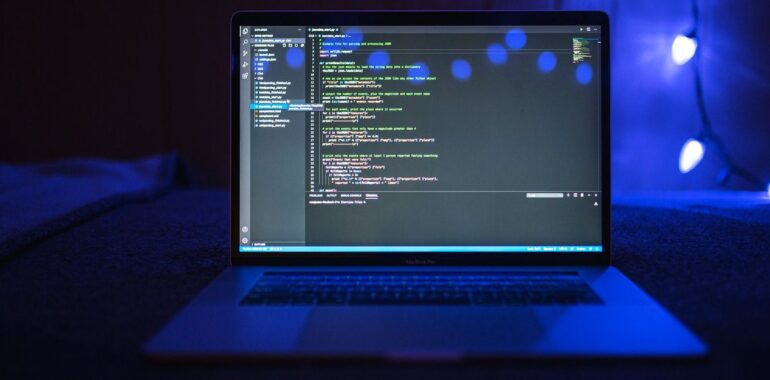 Portable affichant du code dans une pièce éclairée en bleu, illustrant le vol de clés API d'IA