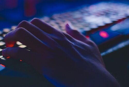 Main sur un clavier d’ordinateur rétroéclairé dans la pénombre