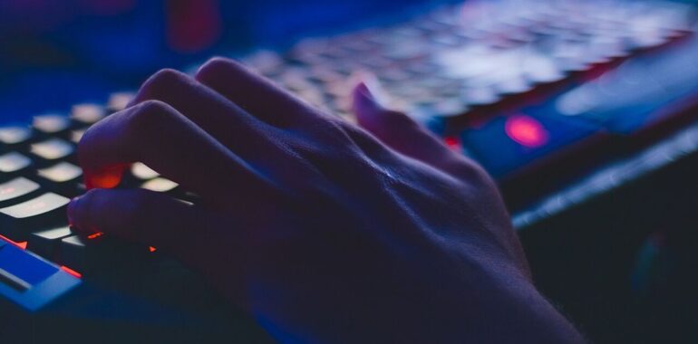 Main sur un clavier d’ordinateur rétroéclairé dans la pénombre