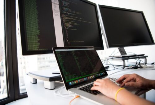 Personne tapant sur un portable devant plusieurs écrans, illustrant l'administration d'un NetScaler Citrix