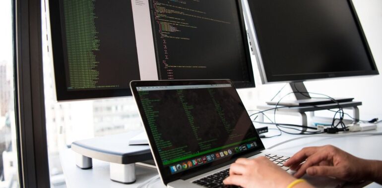 Personne tapant sur un portable devant plusieurs écrans, illustrant l'administration d'un NetScaler Citrix