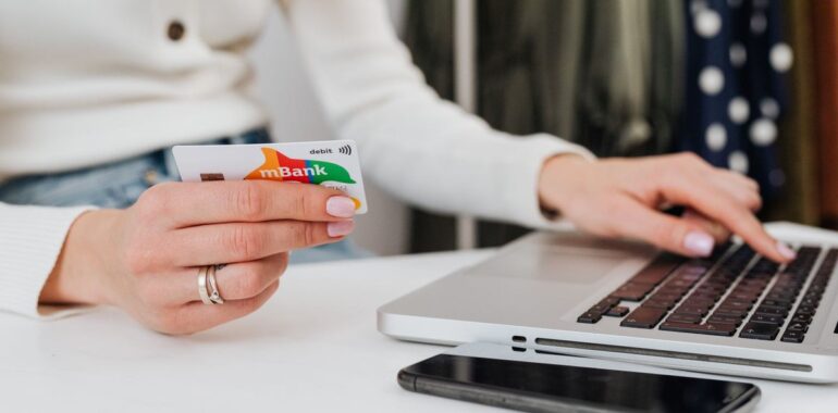 Personne tenant une carte de crédit devant un ordinateur portable, illustrant la faille Magento BlockStrap qui menace les boutiques en ligne