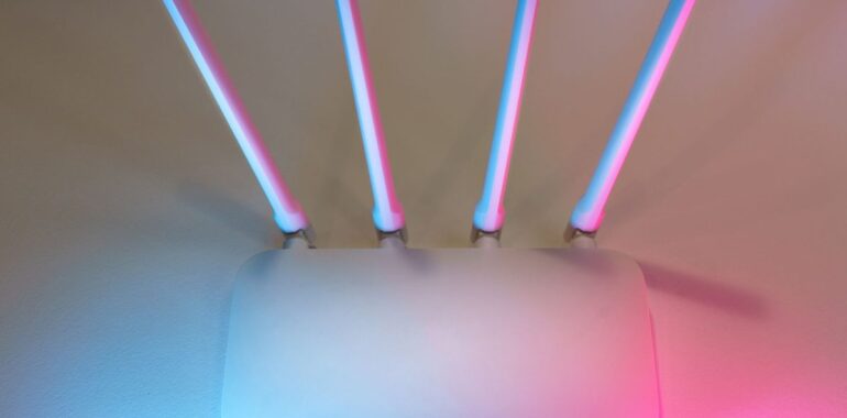Routeur sans fil blanc à quatre antennes éclairé en bleu et rose, illustrant la faille Wi-Fi Broadcom WPSplinter