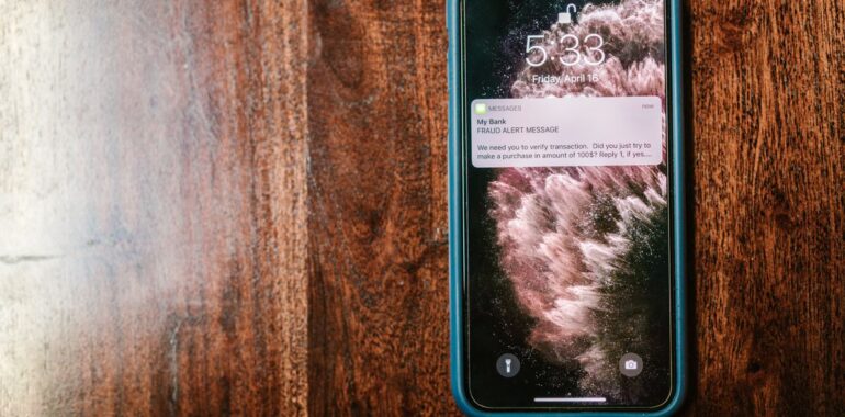 Téléphone affichant une alerte de fraude par texto, illustrant une fausse amende de péage envoyée par hameçonnage