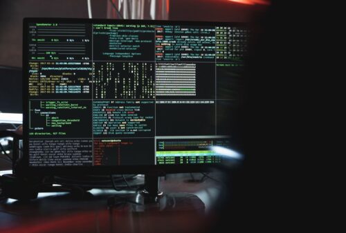 Écran affichant du code et des lignes de commande dans une pièce sombre, illustrant de vieilles failles encore exploitées