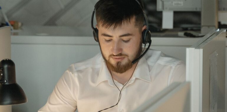 Agent de soutien technique portant un casque-micro devant son ordinateur